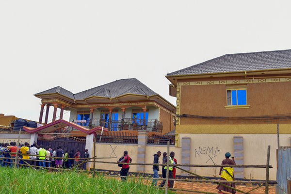 Residents gather outside houses marked for demolition in Nakuwadde Village