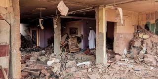 A man walks through the rubble as they inspect a house that was hit by an artillery shell